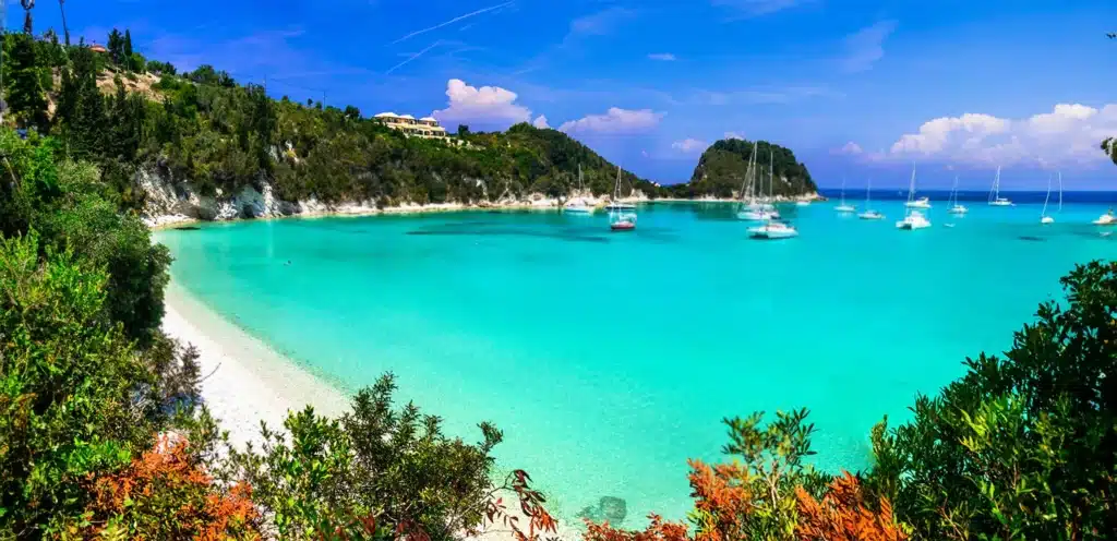 Lakka in Paxos beach with crystal clear green sea and yachts